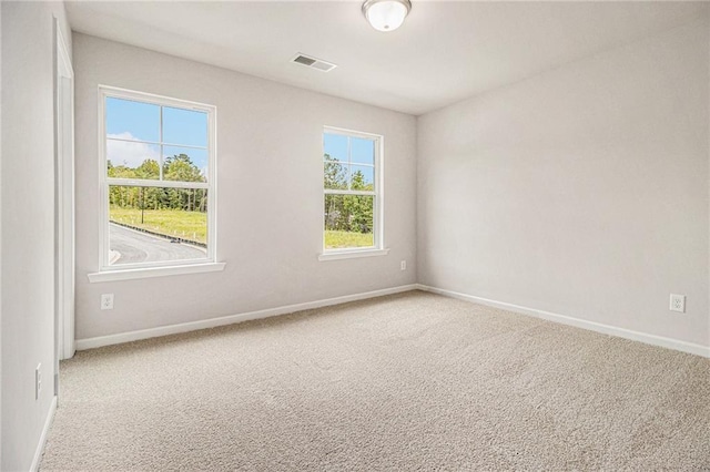 empty room with light carpet, visible vents, and baseboards