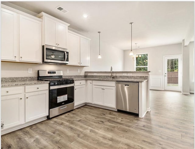 kitchen featuring a peninsula, white cabinetry, visible vents, stainless steel appliances, and a sink