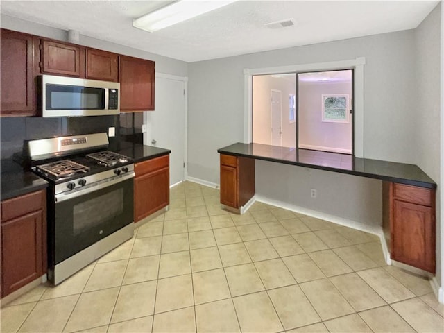 2492 Wild Rose Cir, Lawrenceville, GA 30044 - kitchen featuring appliances with stainless steel finishes, dark countertops, light tile patterned flooring, and baseboards