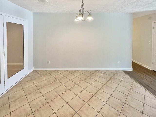 2492 Wild Rose Cir, Lawrenceville, GA 30044 - spare room with a textured ceiling, light tile patterned floors, a chandelier, and baseboards