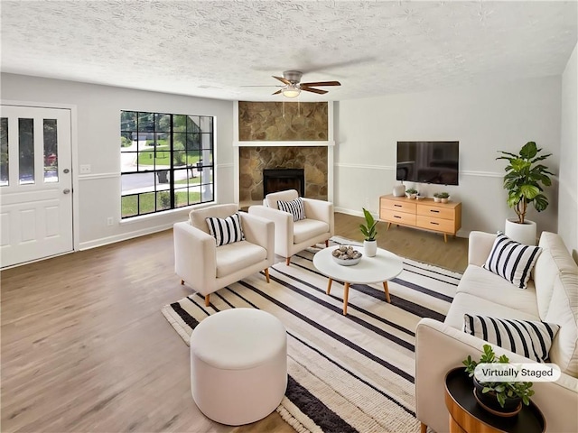 2492 Wild Rose Cir, Lawrenceville, GA 30044 - living area with ceiling fan, wood finished floors, a textured ceiling, baseboards, and a fireplace