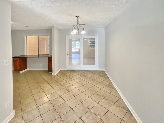 2492 Wild Rose Cir, Lawrenceville, GA 30044 - unfurnished room with light tile patterned floors, a chandelier, baseboards, and a textured ceiling