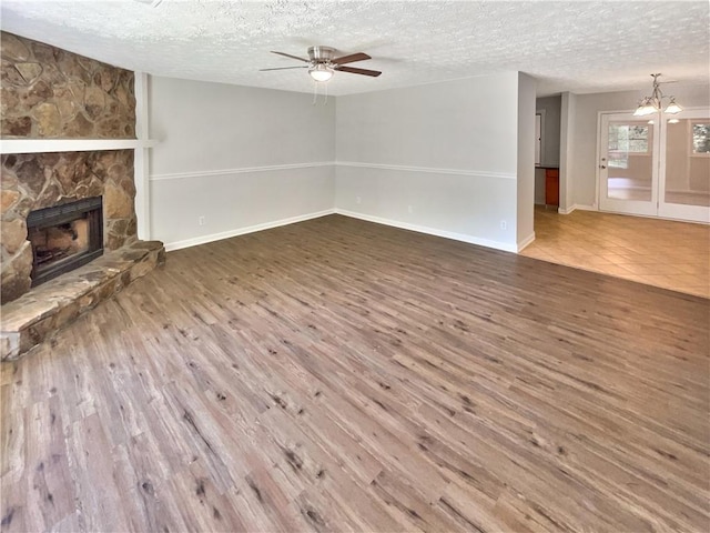 2492 Wild Rose Cir, Lawrenceville, GA 30044 - unfurnished living room with a textured ceiling, a ceiling fan, wood finished floors, a fireplace, and a chandelier
