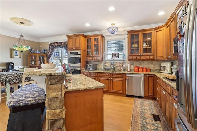 kitchen with a kitchen island, appliances with stainless steel finishes, decorative light fixtures, sink, and a kitchen breakfast bar