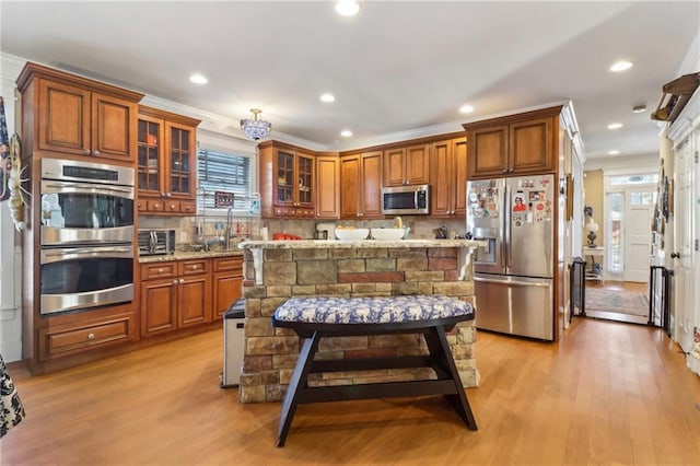 kitchen featuring tasteful backsplash, light wood-type flooring, a kitchen breakfast bar, and appliances with stainless steel finishes