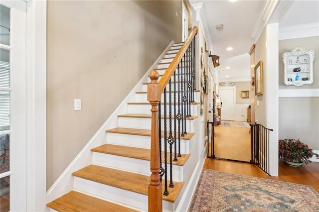 stairs featuring ornamental molding and hardwood / wood-style floors