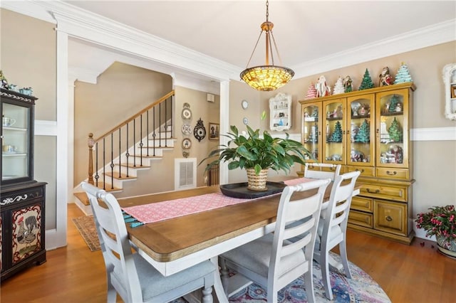 dining area with crown molding and dark wood-type flooring