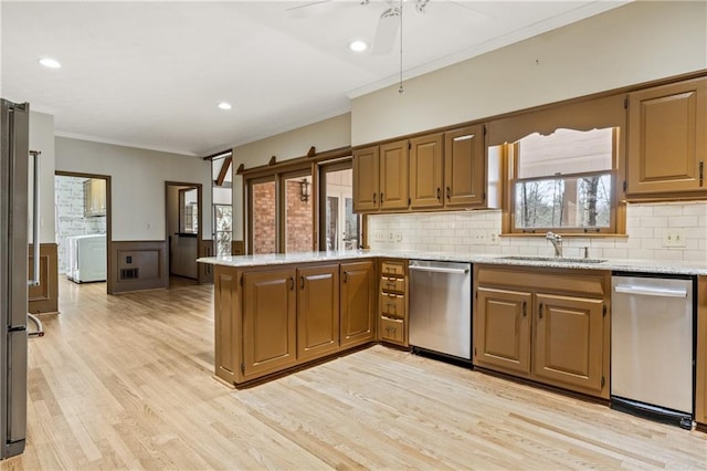 kitchen featuring crown molding, a sink, a peninsula, and stainless steel dishwasher