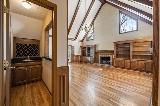 interior space with a fireplace, wood finished floors, wainscoting, beamed ceiling, and indoor wet bar