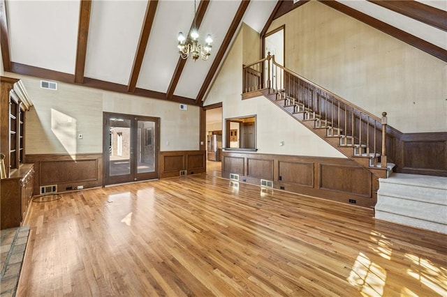 unfurnished living room featuring wood finished floors, visible vents, stairs, french doors, and beamed ceiling