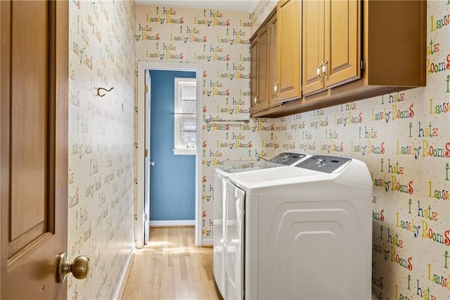 clothes washing area featuring wallpapered walls, cabinet space, baseboards, washer and clothes dryer, and light wood-style floors