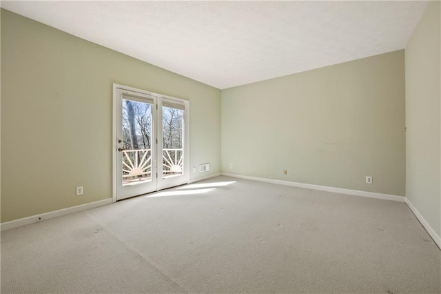 spare room with baseboards, a textured ceiling, visible vents, and light colored carpet