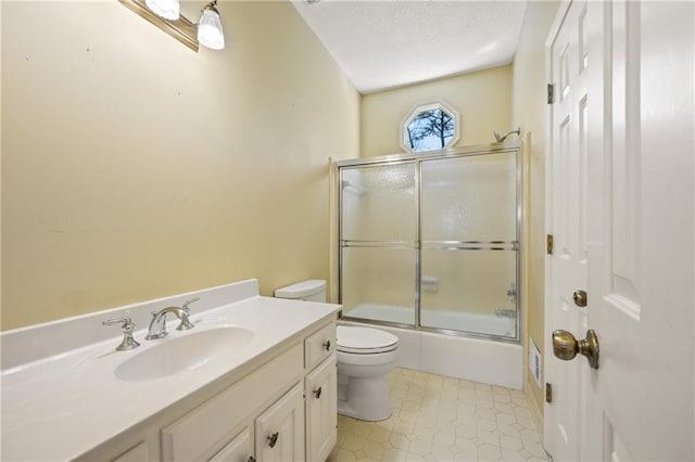 bathroom featuring toilet, combined bath / shower with glass door, a textured ceiling, and vanity