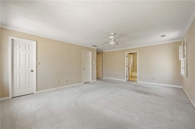 spare room featuring crown molding, light colored carpet, visible vents, a textured ceiling, and baseboards