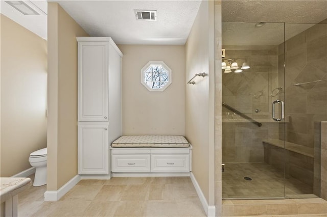 full bath with visible vents, toilet, a shower stall, a textured ceiling, and baseboards