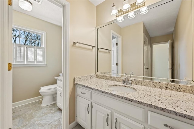 bathroom with baseboards, vanity, and toilet