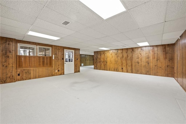 basement with visible vents, carpet flooring, and wooden walls