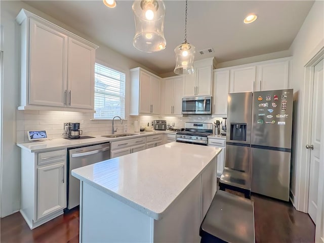 114 Garrison Dr, Winder, GA 30680 - kitchen featuring stainless steel appliances, decorative backsplash, white cabinets, a center island, and decorative light fixtures