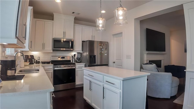 114 Garrison Dr, Winder, GA 30680 - kitchen with appliances with stainless steel finishes, light countertops, backsplash, white cabinets, and hanging light fixtures