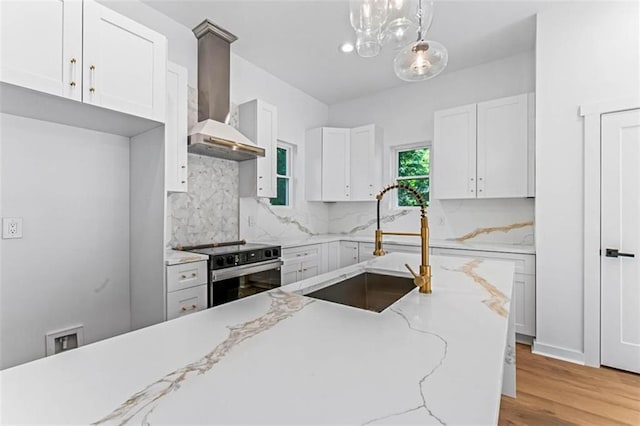 1835 Taylor Ave, East Point, GA 30344 - kitchen featuring electric stove, wall chimney range hood, tasteful backsplash, white cabinetry, and light wood-type flooring