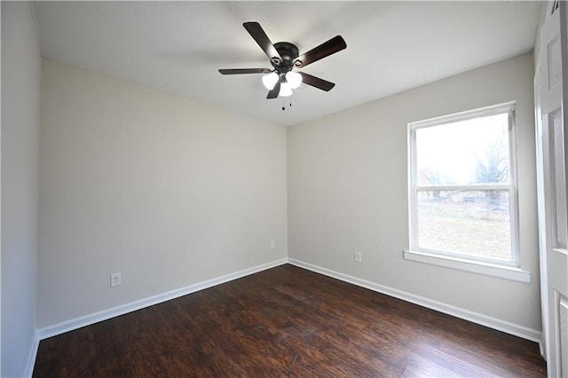 empty room featuring dark wood finished floors, a ceiling fan, and baseboards