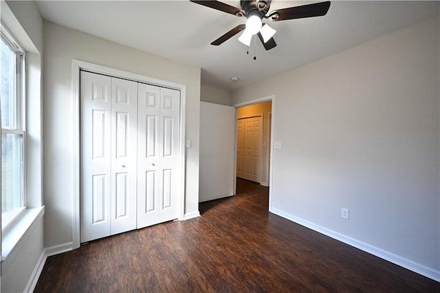 unfurnished bedroom featuring dark wood-style flooring, a closet, a ceiling fan, and baseboards