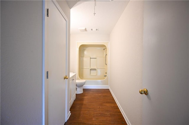 corridor featuring dark wood-type flooring, visible vents, and baseboards