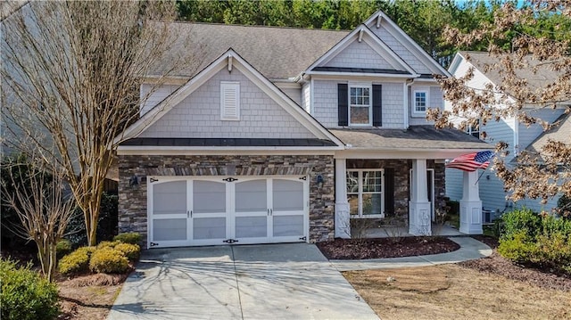 craftsman-style house featuring stone siding, covered porch, an attached garage, and concrete driveway