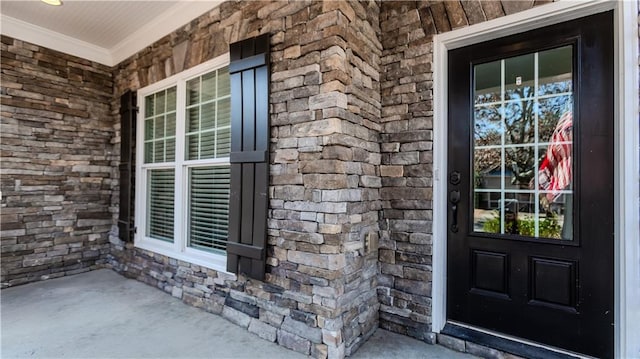 view of exterior entry with stone siding and a porch