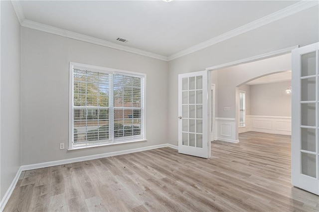 spare room with ornamental molding, french doors, and light wood-type flooring