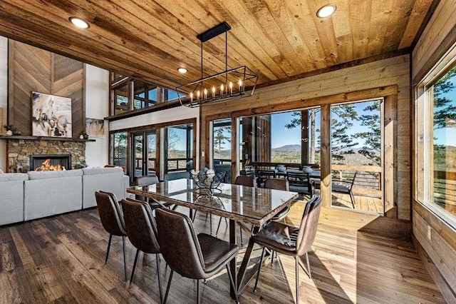 dining space featuring wood ceiling, a stone fireplace, dark hardwood / wood-style floors, and wood walls