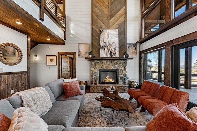 living room featuring a towering ceiling, a fireplace, and wooden walls