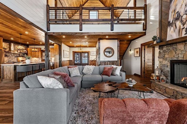 living room featuring wooden walls, wood-type flooring, a fireplace, and a high ceiling