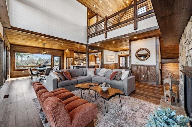 living room with wooden ceiling, wooden walls, hardwood / wood-style flooring, a towering ceiling, and a fireplace