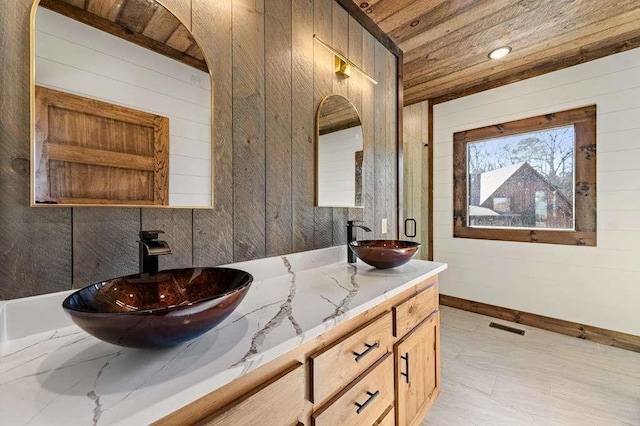 bathroom featuring wood ceiling, vanity, and wooden walls