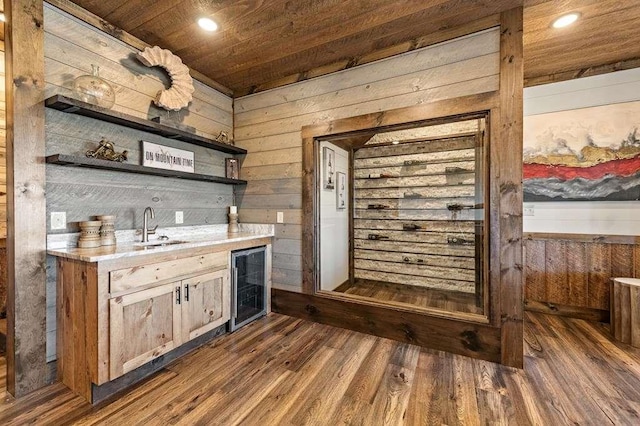 bar with sink, wood ceiling, wooden walls, and beverage cooler