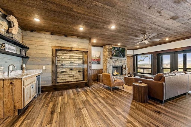 living room with a stone fireplace, sink, wooden ceiling, dark hardwood / wood-style flooring, and beverage cooler