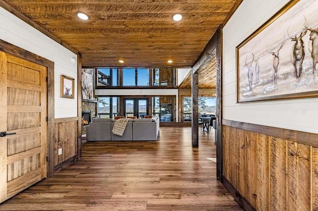 corridor with dark hardwood / wood-style flooring, wooden ceiling, and wooden walls