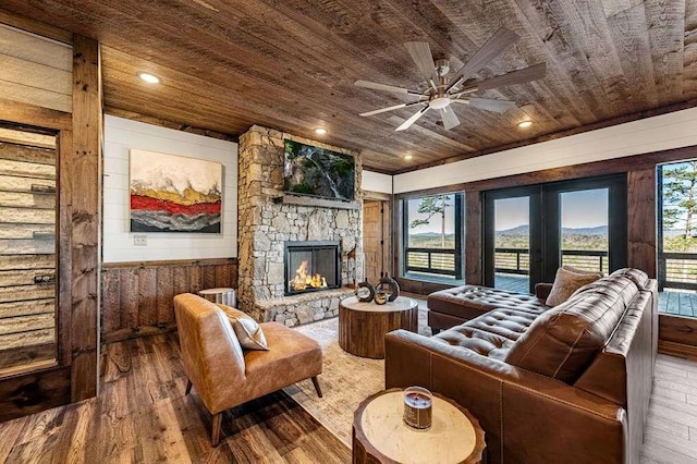 living room with a stone fireplace, a wealth of natural light, wooden ceiling, and hardwood / wood-style flooring