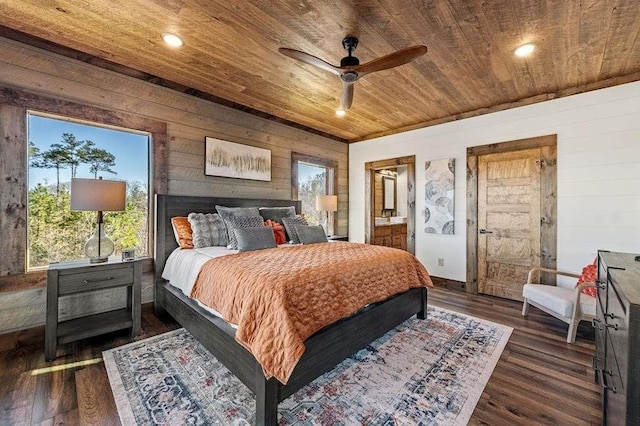 bedroom with connected bathroom, wood ceiling, dark wood-type flooring, and wooden walls