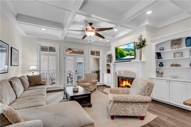 living room featuring beam ceiling, coffered ceiling, wood-type flooring, and ceiling fan