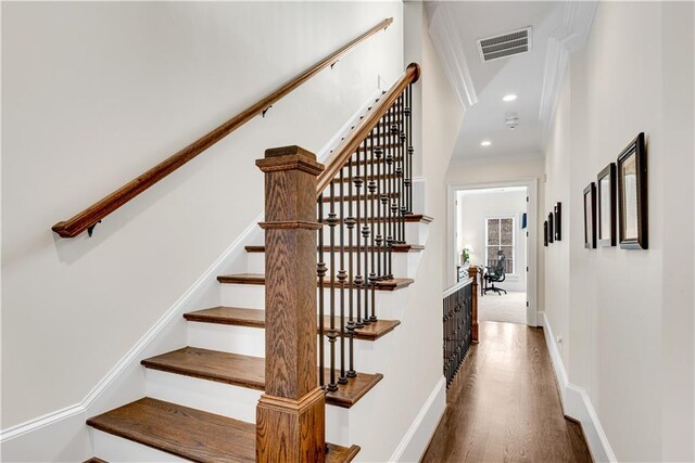 stairs with ornamental molding and hardwood / wood-style flooring