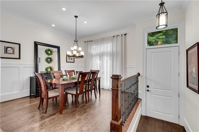 dining area with ornamental molding, wood-type flooring, and an inviting chandelier