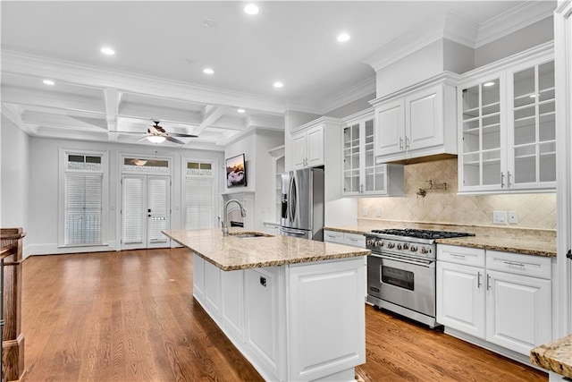 kitchen with appliances with stainless steel finishes, sink, white cabinetry, hardwood / wood-style flooring, and a center island with sink