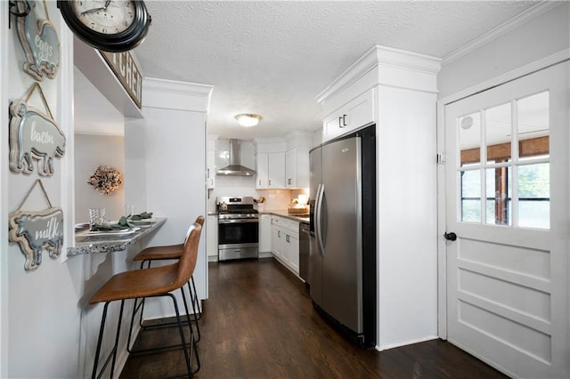 kitchen featuring wall chimney exhaust hood, stainless steel appliances, white cabinetry, and dark wood-type flooring