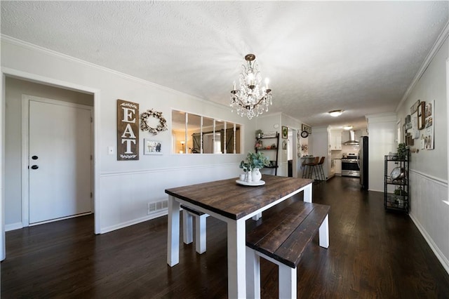 dining space with a textured ceiling, ornamental molding, dark hardwood / wood-style floors, and a chandelier