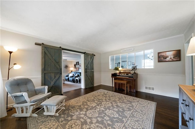 living area featuring a barn door, crown molding, and dark wood-type flooring