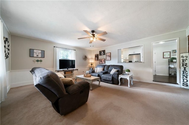 carpeted living room featuring a textured ceiling, crown molding, and ceiling fan