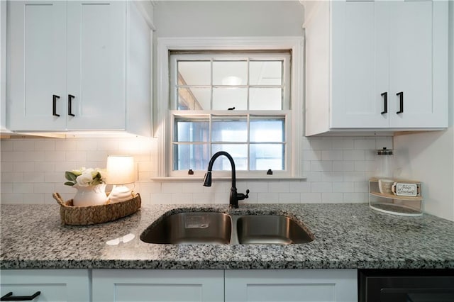 kitchen featuring stone counters, backsplash, white cabinetry, and sink