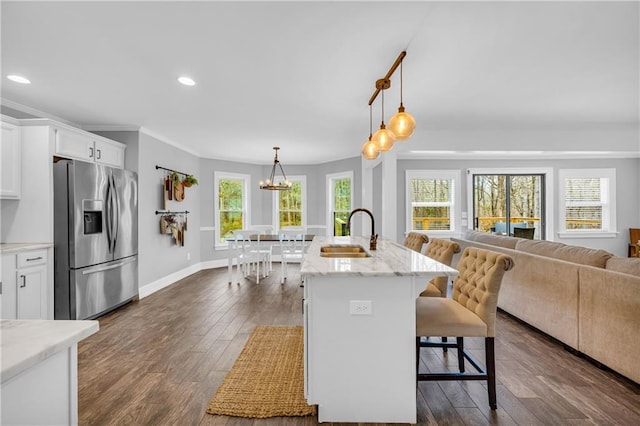 kitchen with white cabinetry, sink, stainless steel fridge, and a kitchen bar